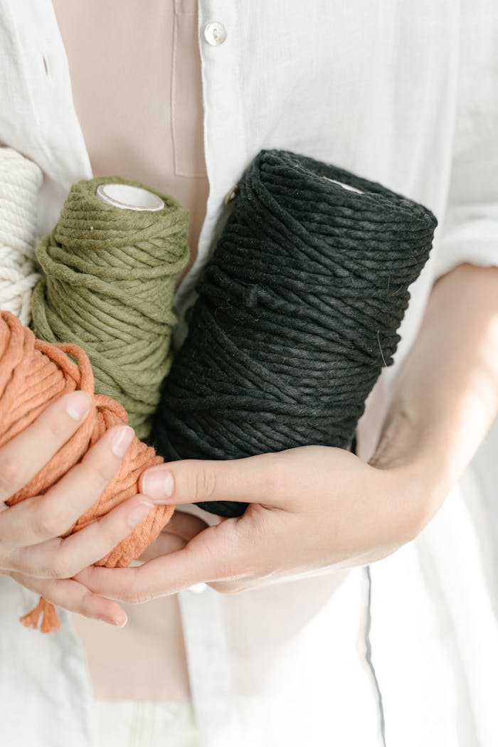 Person Holding Spools of Wool with Different Colors